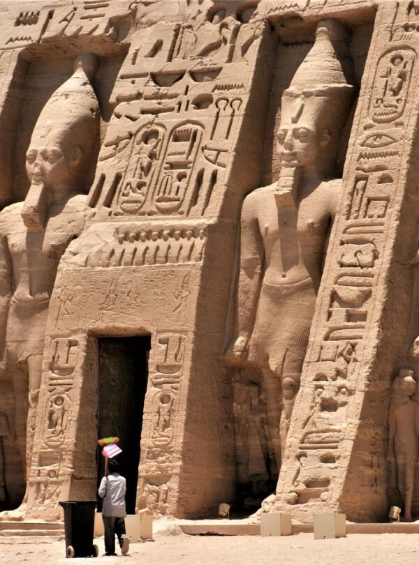 Exterior view of an ancient Egyptian temple featuring hieroglyphics and carved statues.